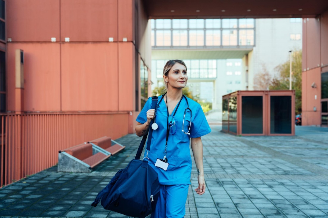 Young travel healthcare worker walking out of a hospital.