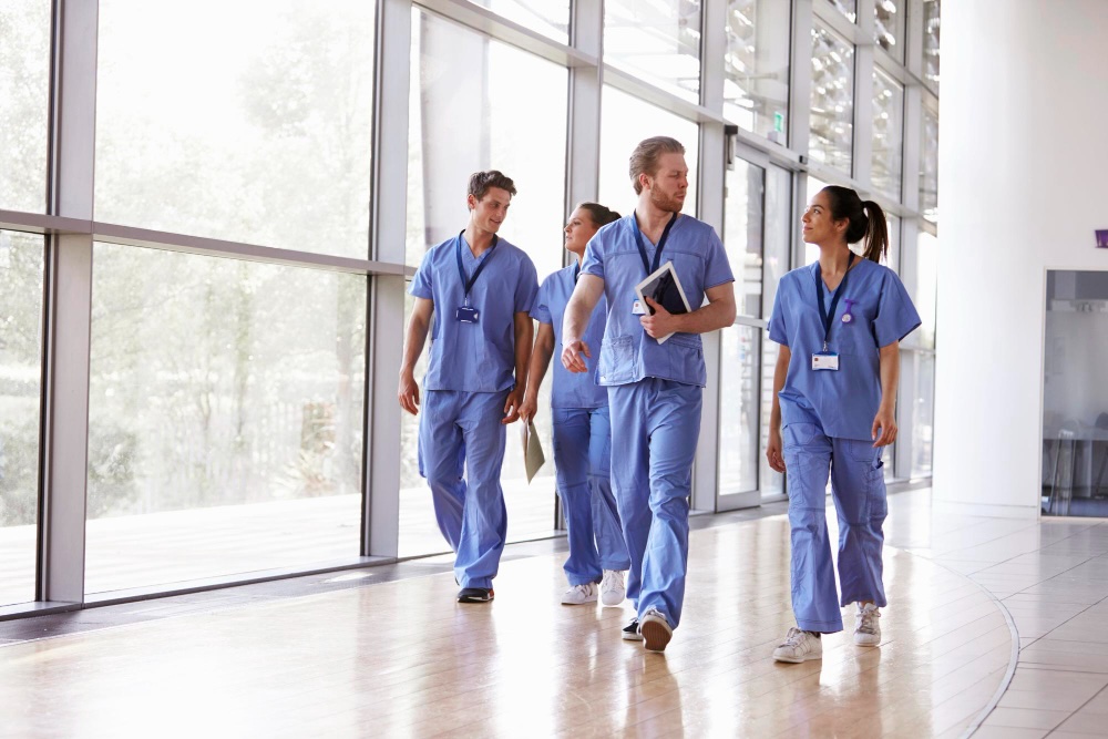 Group of allied health technologists walking in hallway at medical facility.