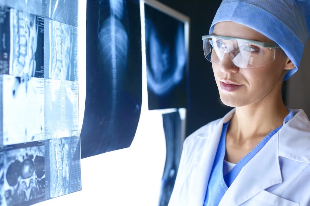 Radiology technologist examining illuminated X-ray results.