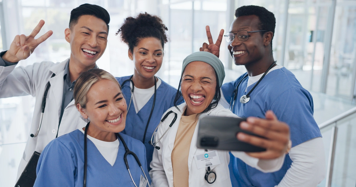 Group of smiling X-Ray technologists and doctors taking a selfie.