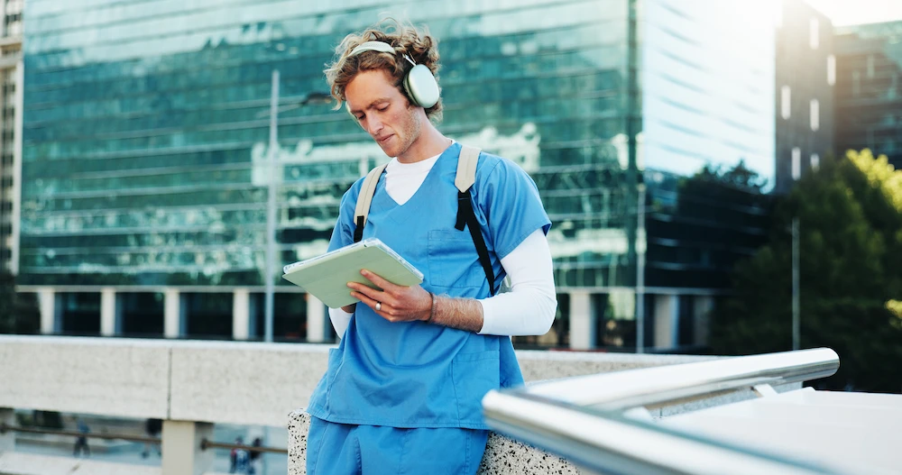 Healthcare worker wearing headphones and watching a video on a tablet.