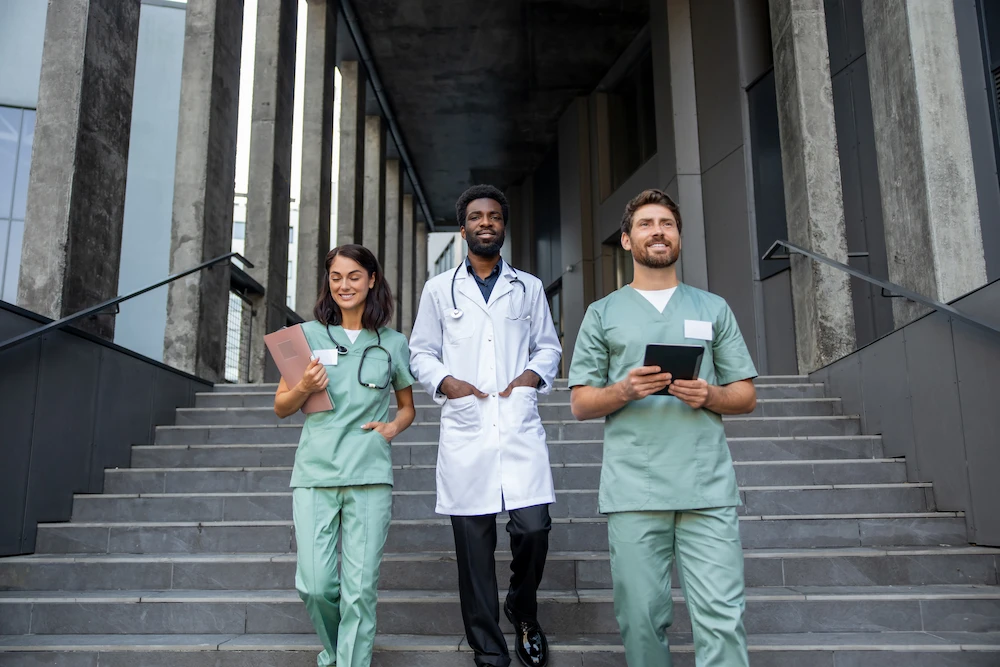 Medical professionals walking down the stairs in front of a facility.