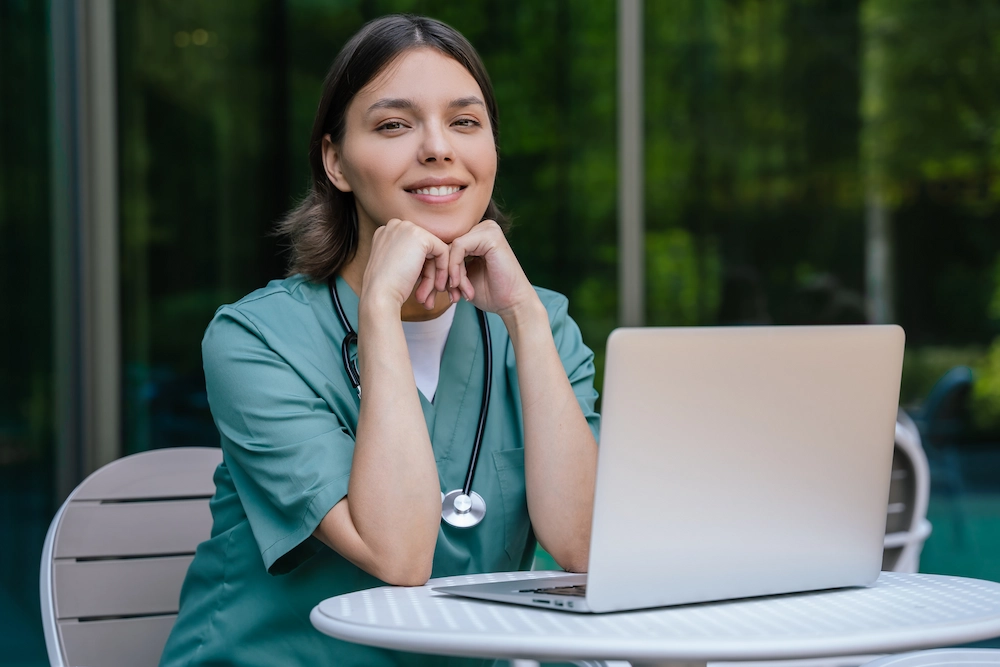 Smiling travel nurse working at a laptop.